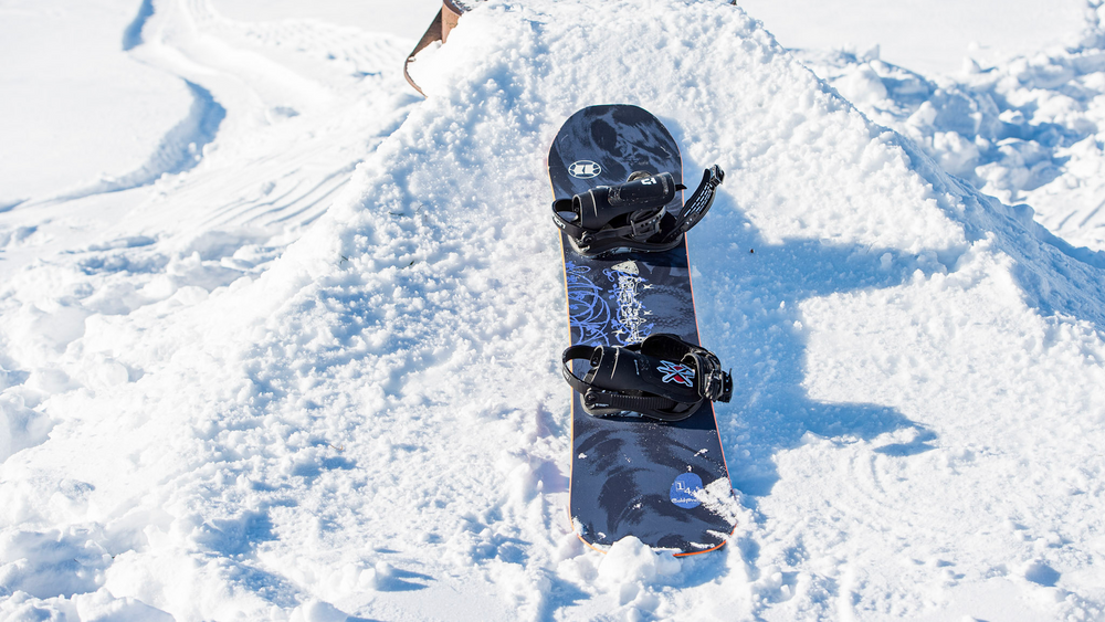 A blue Armada Snowboard laying in the snow.