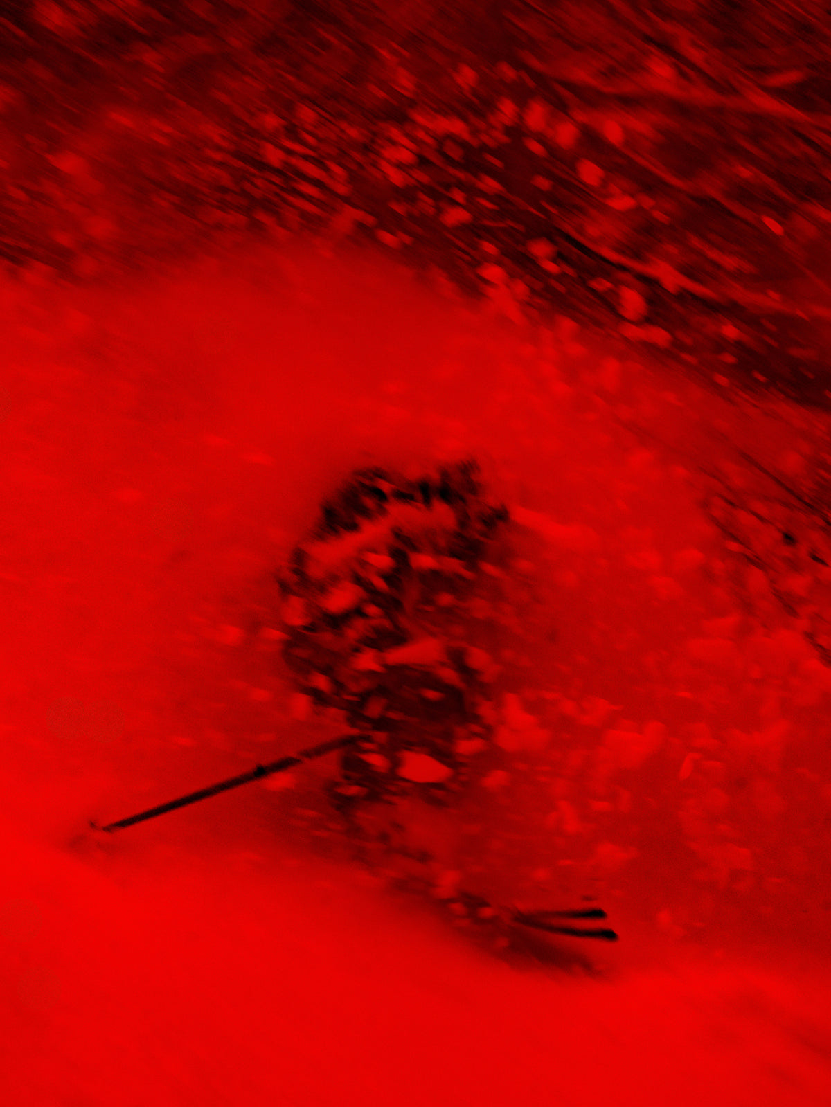 A close-up of a red textured surface with a dark, indistinct central mark or shape visible against the red background.